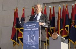 Elie Wiesel became Founding Chairman of the United States Holocaust Memorial Council in 1980. Here, he speaks at a ceremony held during the Tribute to Holocaust Survivors, one of the Museum's tenth anniversary events. Flags of US Army liberating divisions form the backdrop to the ceremony. Washington, DC, November 2003.