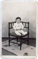 Portrait of Tsewie Herschel seated in a chair, taken while he was living in hiding. Oosterbeek, the Netherlands, 1943–1944.
Tsewie never knew his parents. Born in December 1942, he was hidden with the de Jong family in April 1943. That July, his parents were deported from the Netherlands to the Sobibór killing center. The de Jongs renamed Tsewie "Henkie," raised him as a Christian, and treated him as their son. Tsewie learned about his origins from his paternal grandmother, who reclaimed him after the war, and from documents that had belonged to his parents.