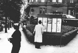 Un piéton s'arrête pour lire l'édition du journal antisémite "Der Stürmer" (l'Attaquant) dans une boîte présentoir à Berlin. "Der Stürmer" faisait de la publicité dans des présentoirs situés à proximité de lieux comme les arrêts d'autobus, les rues passantes, les parcs et les cantines d'usine partout en Allemagne. Berlin, Allemagne, probablement dans les années 1930.