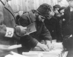 رجل في الشارع يبيع كتبا عبرية قديمة بالحي اليهودي بوارصوفيا, بولندا. فبراير 1941.