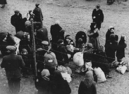 Jewish families with bundles of belongings during deportation from the Kovno ghetto in Lithuania to Riga in neighboring Latvia. Kovno, Lithuania, 1942.
