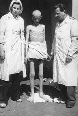 Shortly after liberation, an emaciated concentration camp inmate stands between two members of the International Red Cross. Theresienstadt, Czechoslovakia, May 1945.