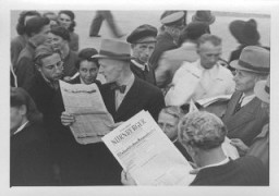 People gather in the street to read a special edition of the Nurnberger newspaper reporting the sentences handed down by the International Military Tribunal. Nuremberg, Germany, October 1, 1946.