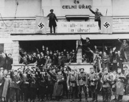 元チェコ辺境の駐屯地、ズーデーテンラント停泊地に行進するドイツ兵。 2つのかぎ十字の間の文字は、 「1つの人民、1つの帝国、1人の総統」と書かれている。 1938年10月2日または3日、チェコスロバキア、グロットー。