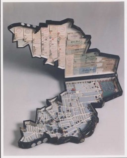 Leon Jakubowicz, a shoemaker by training and a native of Lodz, began constructing this model of the Lodz ghetto soon after his arrival there from a prisoner-of-war camp in April 1940. The case holds a scale (1:5000) model of the ghetto, including streets, painted houses, bridges, churches, synagogue ruins, factories, cemeteries, and barbed wire around the ghetto edges. The model pieces are made from scrap wood. The case cover interior is lined with a collection of official seals, a ration card, and paper money, and the case exterior is covered with metal coins.