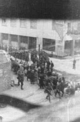 Deportation of Jews from the Warsaw ghetto during the uprising. The photograph was taken from a building opposite the ghetto by a member of the resistance.  It shows Jews who were captured by the SS during the suppression of the Warsaw ghetto uprising marching past the St. Zofia hospital, through the intersection of Nowolipie and Zelasna Streets, towards the Umschlagplatz for deportation. Warsaw, Poland, April 20, 1943.