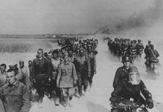At left, a column of Soviet prisoners of war, under German guard, marches away from the front.