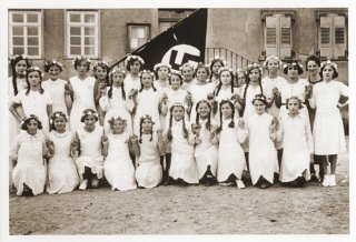 Photo de groupe de filles allemandes posant à l'extérieur de leur école, devant le drapeau nazi