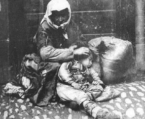 Ermeni kadın ve çocuğu, sahip oldukları bir bohça eşyanın yanında kaldırımda oturuyor.