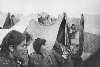 Bir mülteci kampında çergilerin yanında duran Ermeni aileler.