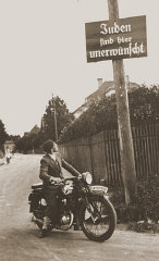 Un motociclista legge un cartello con la scritta 