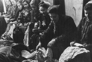 Para wanita Yahudi yang ditangkap untuk kerja paksa menyortir pakaian yang disita.