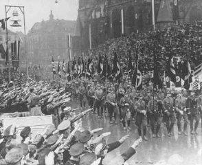 Hitler reviews a parade celebrating the reintegration of the Saar region into Germany.
