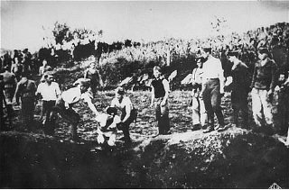 Ustasa (Croatian fascist) guards force a prisoner into a pit to be shot.