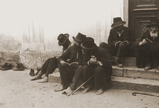Jewish men sitting on the steps of a synagogue. Munkacs, Czechoslovakia, 1936.
