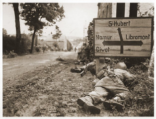 American soldiers of the 8th Infantry Regiment seek cover behind hedges and signs to return fire to German forces holding the town ...